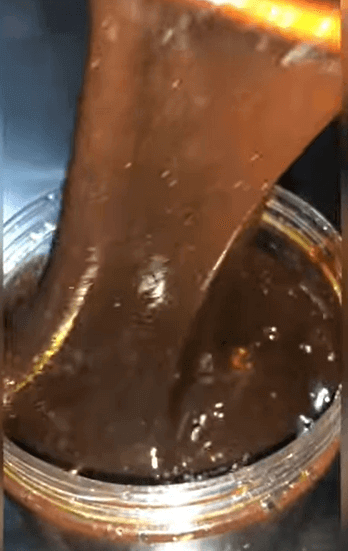 Thick and luscious Goron Tula honey being poured from a jar, showcasing its rich texture and color.